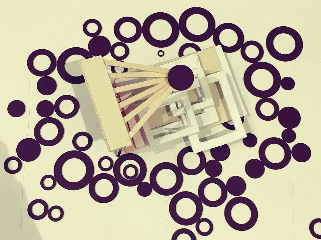 Top view of cream nested frames and a fan-shaped armature centered within a field of deep-purple rings and dots.
